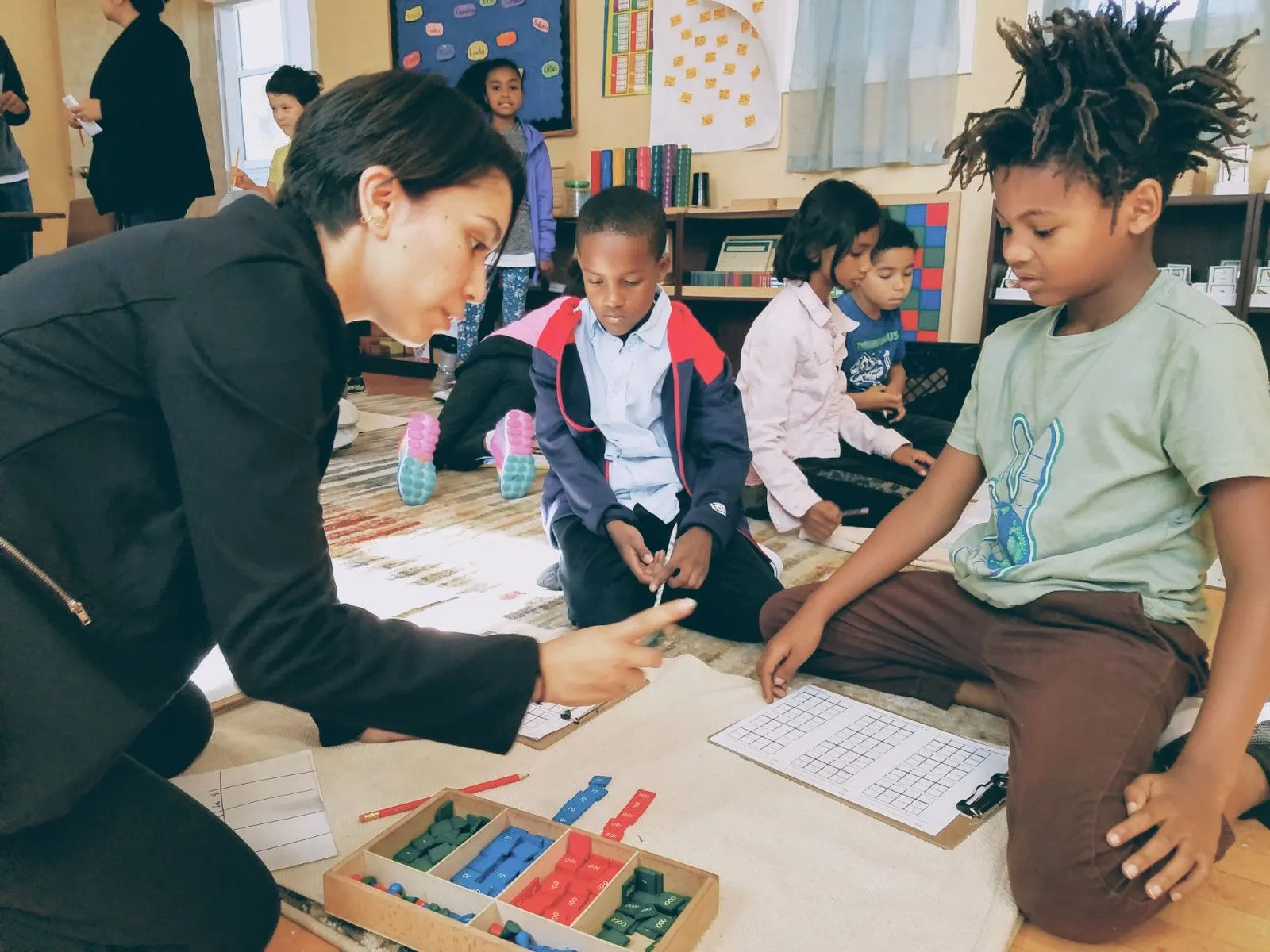 Teacher working with students on Montessori math materials