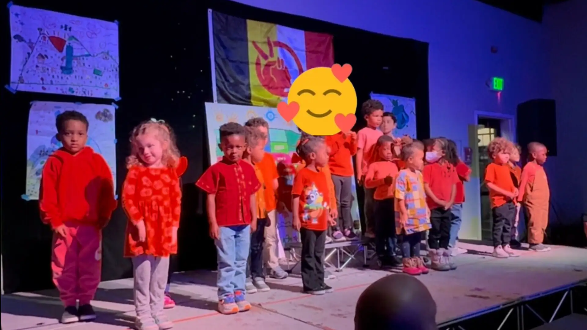 Students in red performing on stage for their families